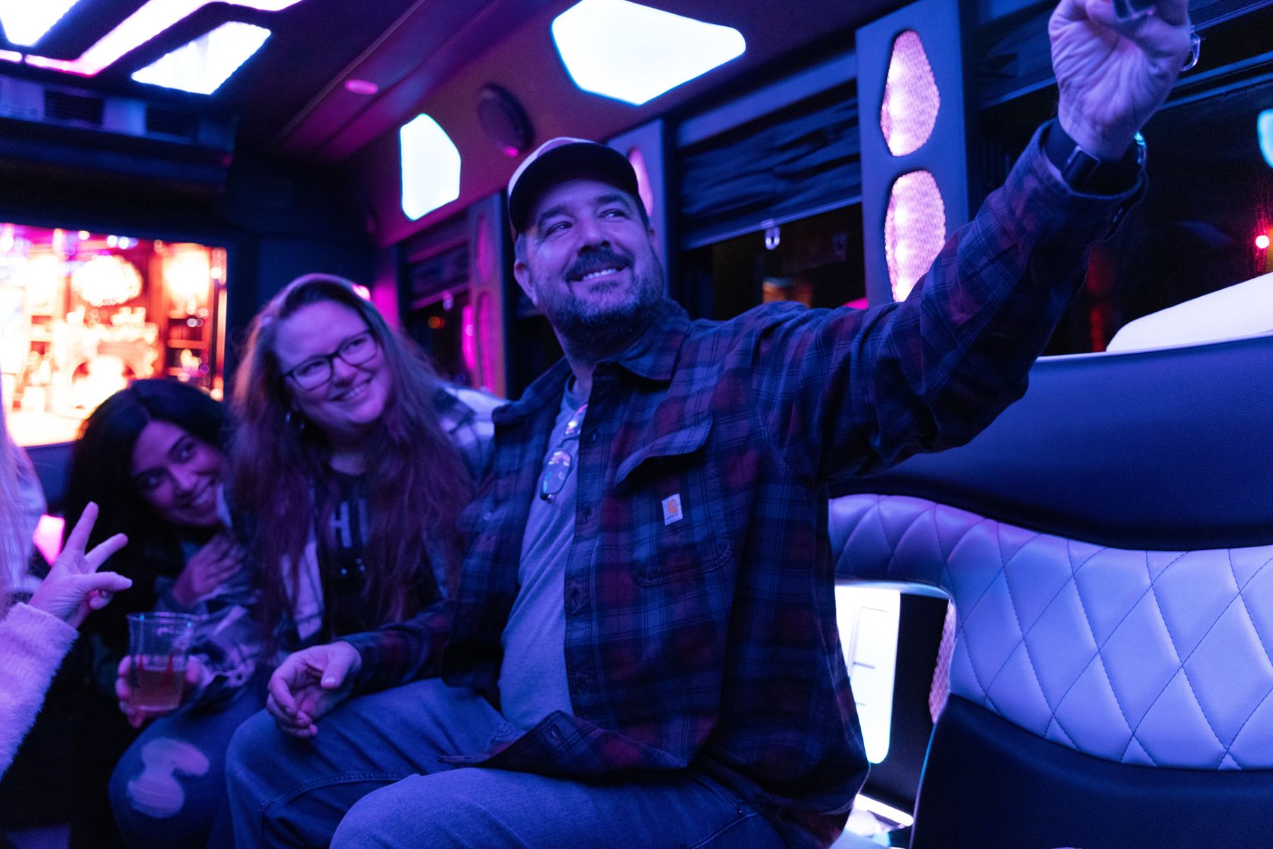 A group celebrating inside a neon-lit party bus